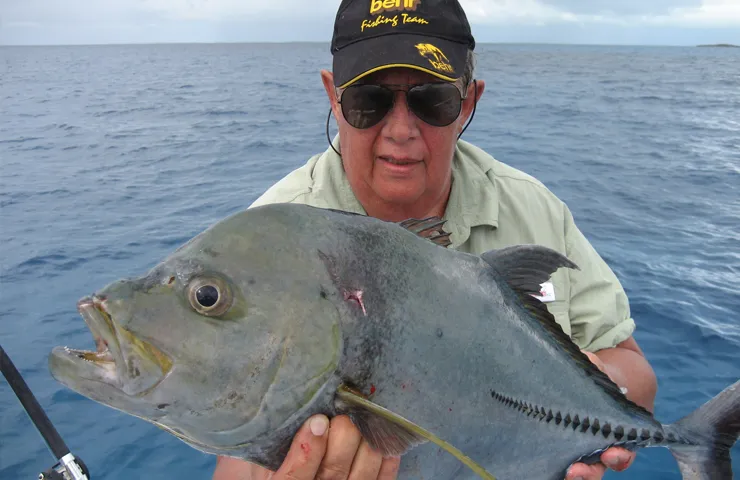 Angler mit Behr Angelsport Cap hält einen Fisch in den Händen.